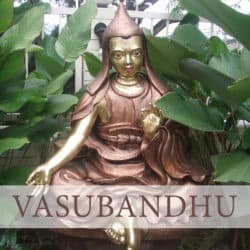 Copper statue of Vasubandhu in a garden with hand outstretched on his right knee.