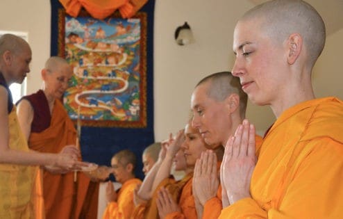 A row of novice nuns kneels to receive a stick to enter the annual monastic retreat.