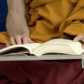 Tybetański mnich buddyjski czyta książkę.
