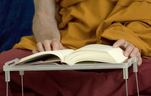 A Tibetan Buddhist monastic reads a book.