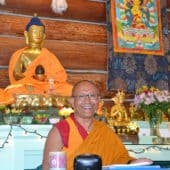 Geshe Dadul Namgyal uśmiecha się podczas nauczania w Sali Medytacji.
