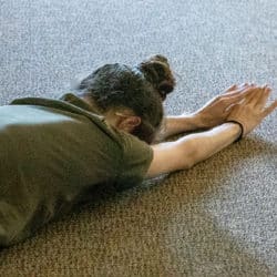A woman making full-length prostrations on the ground.