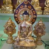 Golden Buddha statue between two Dharma wheels.