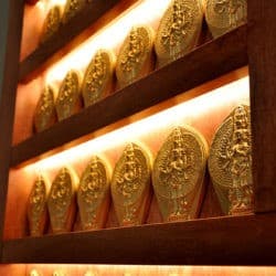 Rzędy glinianych postaci Buddy współczucia, Czenrezika na oświetlonych półkach ołtarzowych.