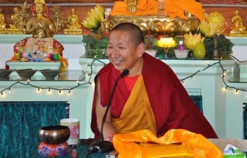 Geshe Yeshi Lhundup uśmiecha się podczas nauczania w Sali Medytacji.