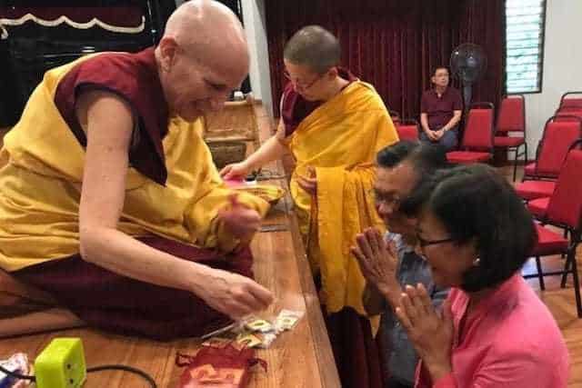Venerable Chodron gives out mani pills to a couple at Buddhist Gem Fellowship.