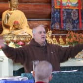 Guy Newland gestures while teaching in the Sravasti Abbey Meditation Hall.