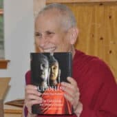 Venerable Thubten Chodron holds a copy of "Buddhism: One Teacher, Many Traditions" and smiles.