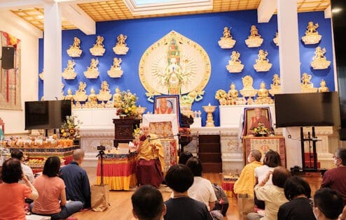 Venerable Chodron teaching in front of a large statue of Chenrezig.