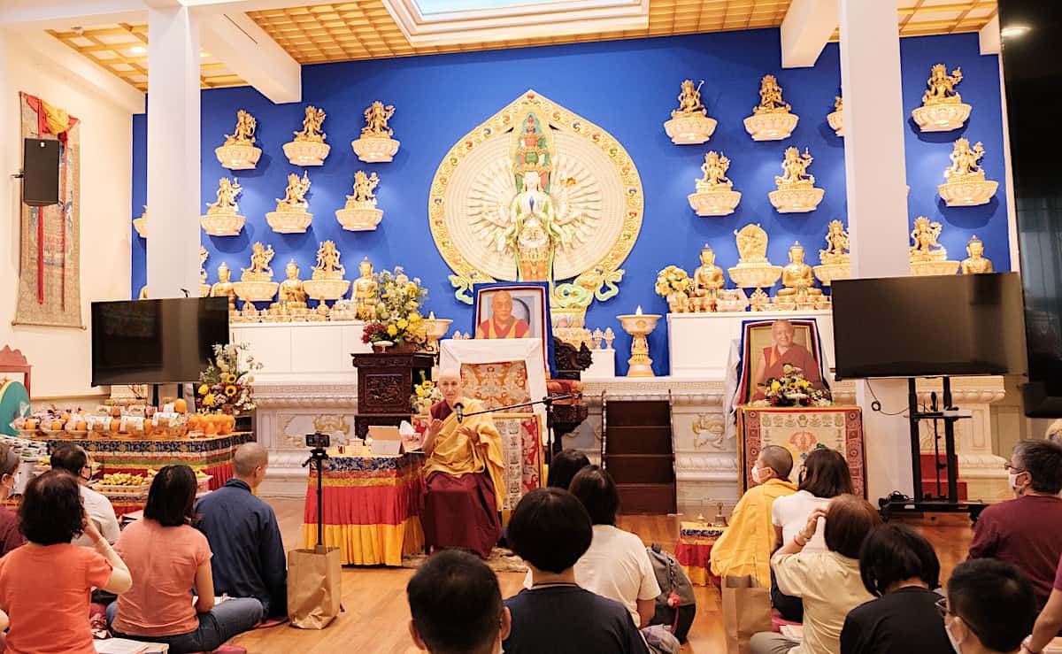 Venerable Chodron teaching in front of a large statue of Chenrezig.