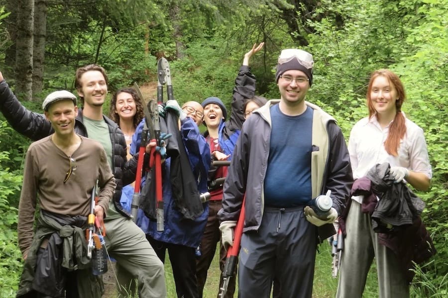 A group of young people working in the Sravasti Abbey forest smiling at the camera.