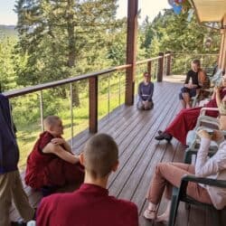 A group of monastics and lay people discuss the Dharma on the Chenrezig Hall deck at Sravasti Abbey.