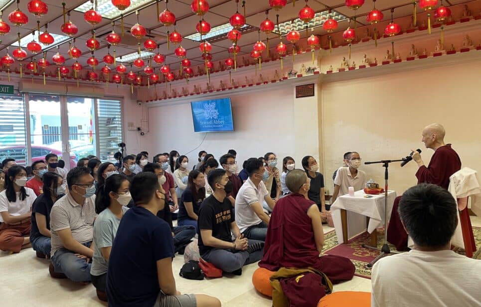 Venerable Chodron teaching in a crowded room of students.