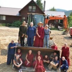 Exploring Monastic Life participants pose with an excavator on the Chenrezig Hall construction site.