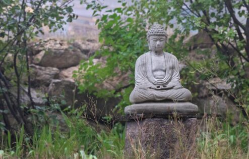 تمثال بوذا الحجري في الحديقة على قاعدة.
