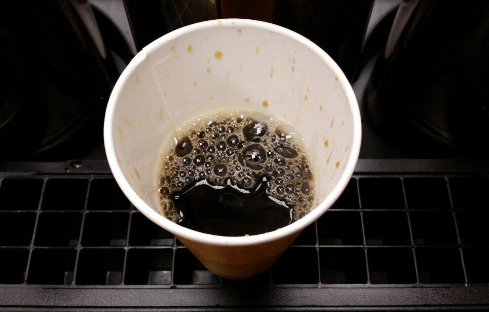Half-full cup of coffee in paper cup.