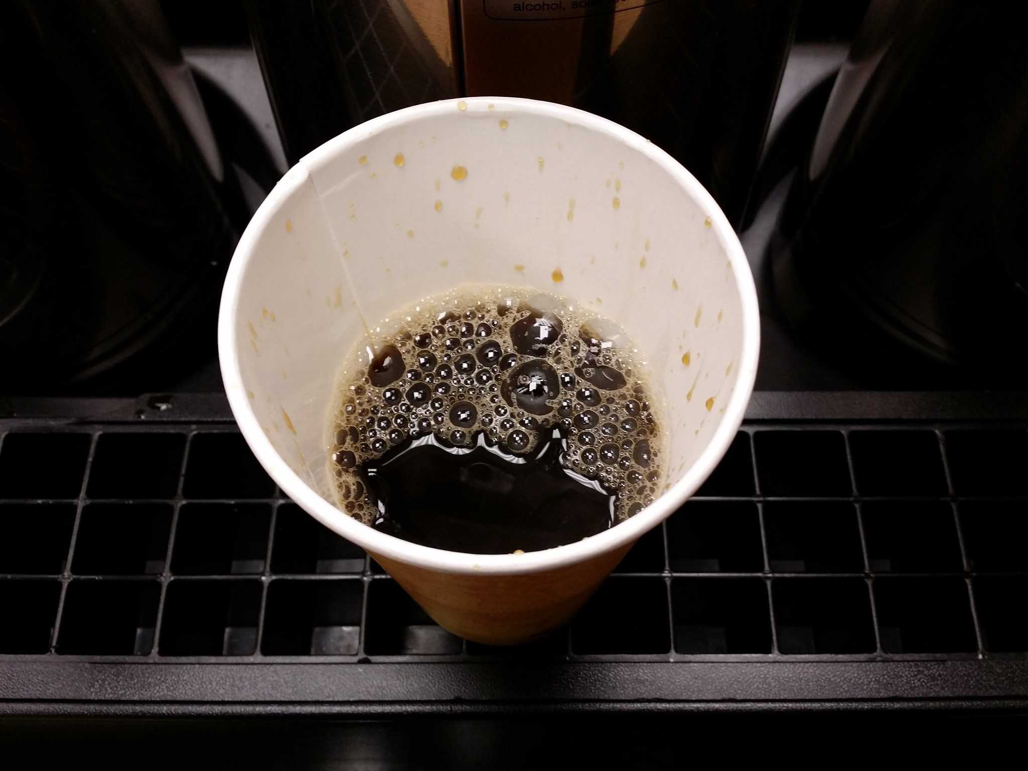 Half-full cup of coffee in paper cup.