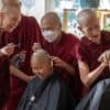 Two senior monastics help shave the heads of anagarikas before their ordination ceremony.